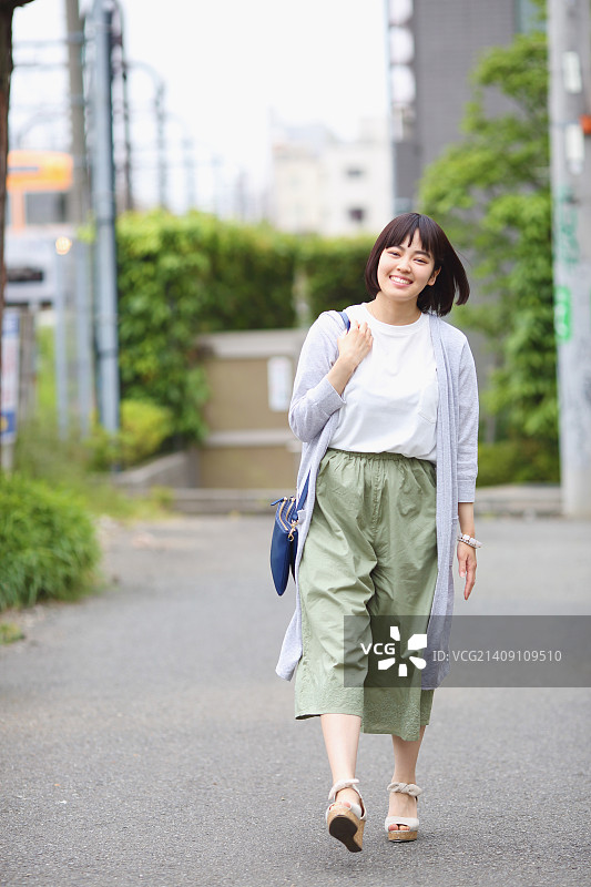一个年轻的日本女人站在外面的铁轨旁图片素材