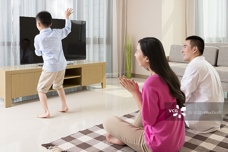 Parents watching son dancing with TV图片素材