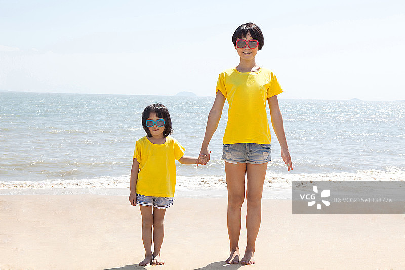 妈妈和女儿手牵手站在沙滩上图片素材