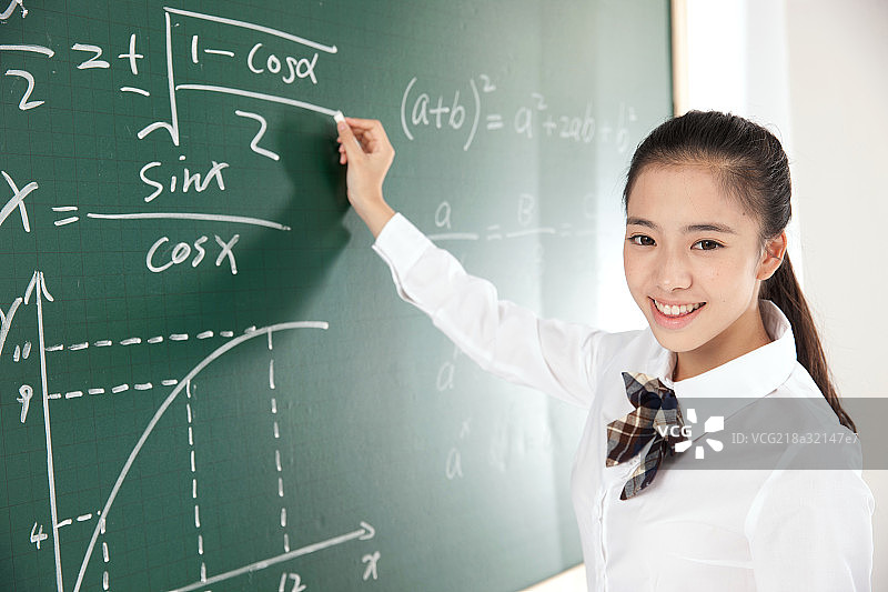 中学女生在黑板前写数学公式图片素材