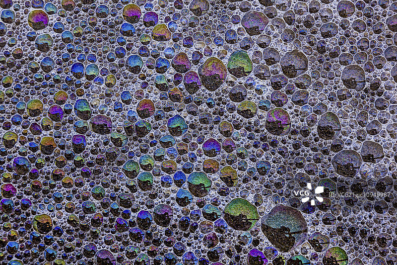 在美国俄勒冈州坎农海滩，空气的泡沫和气泡反射彩虹色的表面图片素材