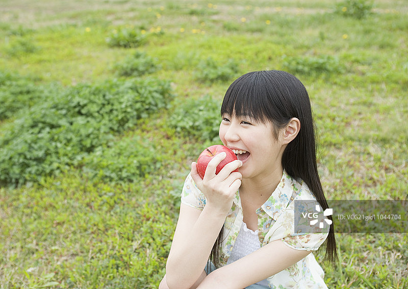 女孩在田里吃苹果图片素材
