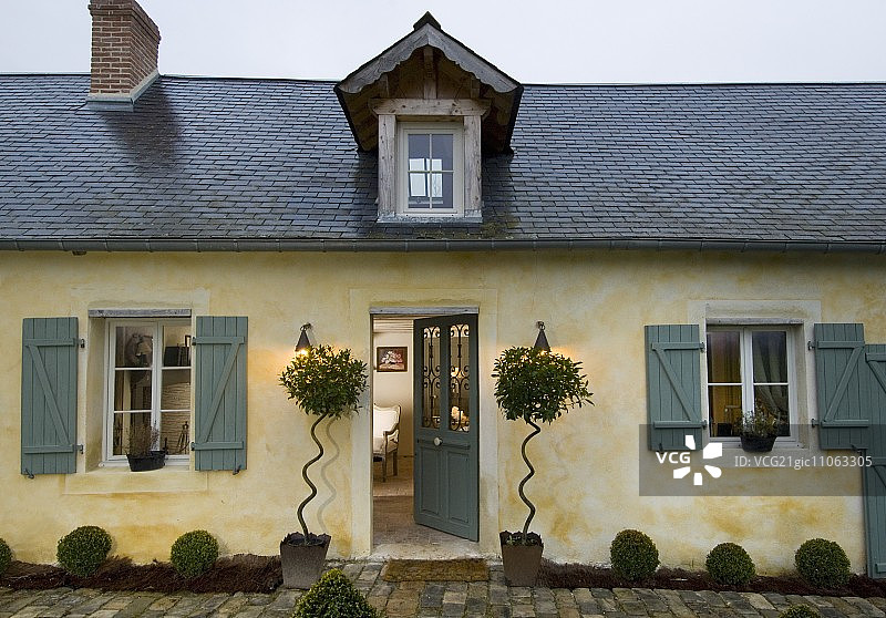 法国北部的简单乡村住宅，有石板屋顶，尖顶的天窗，前门两侧有优雅的植物图片素材