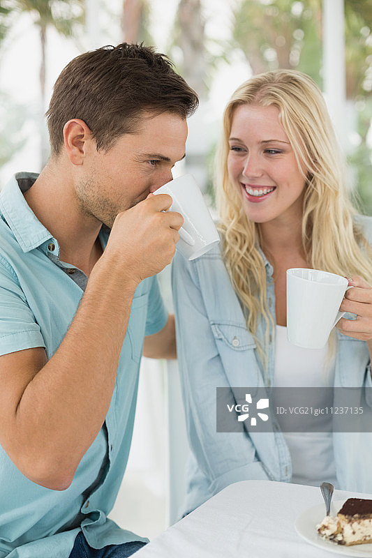 在阳光明媚的日子里，一对时髦的年轻夫妇在咖啡馆露台上一起喝咖啡图片素材