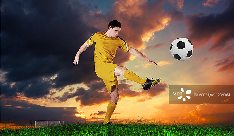 穿着黄色衣服的足球运动员在蓝天下踢着绿色的草地图片素材