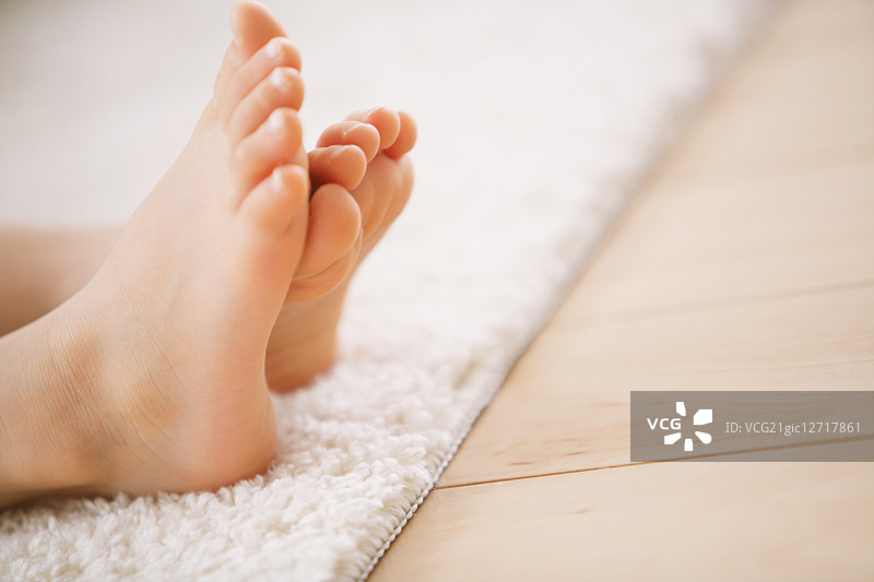 小女孩脚踩在白色地毯上的特写图片素材