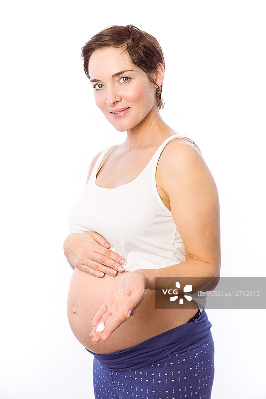 一名孕妇在白色背景上展示身体乳霜图片素材
