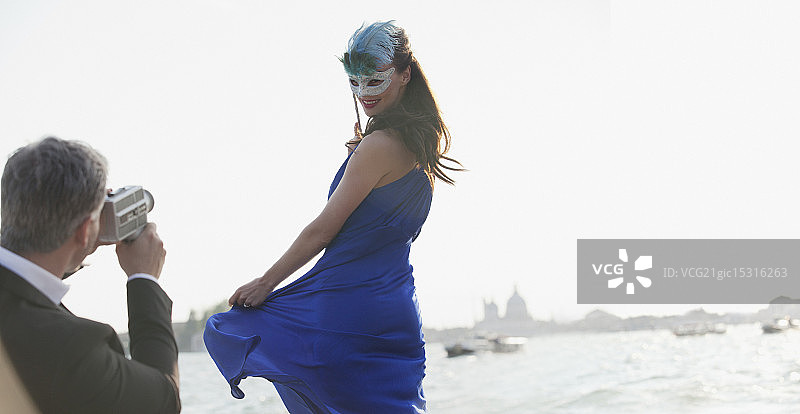 一名男子在威尼斯海滨拍摄戴面具的女子图片素材