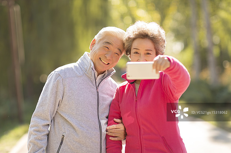 老年伴侣在户外用手机拍照图片素材