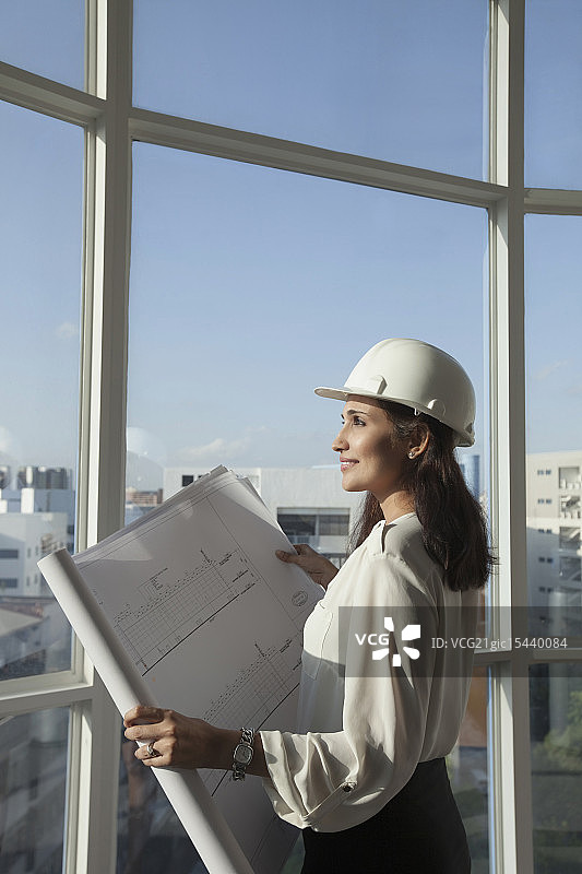 新加坡，女建筑师，戴安全帽，透过窗户看建筑平面图图片素材