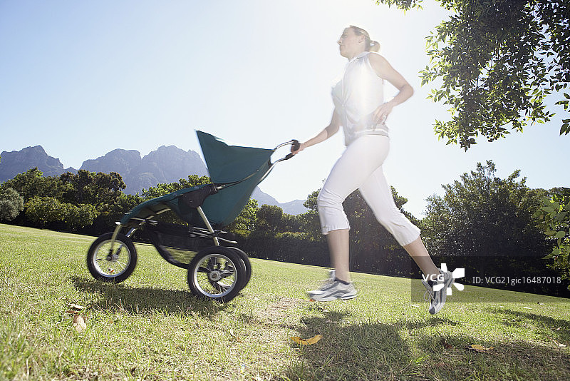 在公园里推着婴儿车跑步的女人图片素材