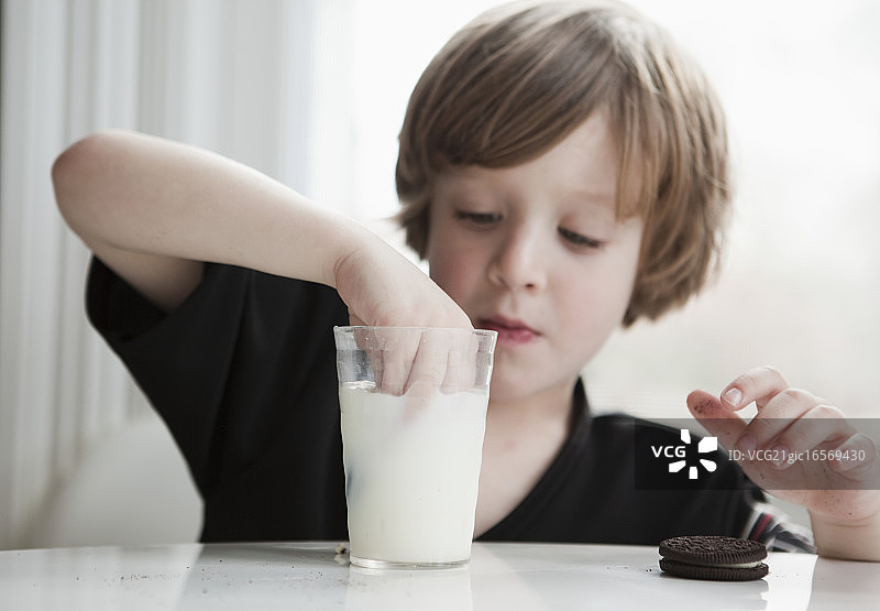 小男孩把饼干浸在牛奶里图片素材
