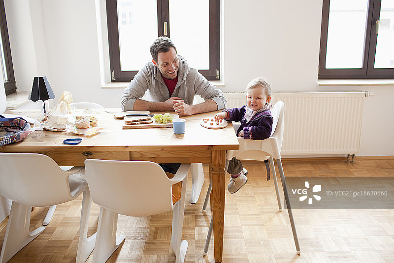 父亲和女儿(6-12个月)坐在餐桌旁图片素材