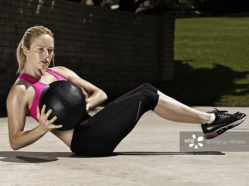 年轻女子拿着健身球做仰卧起坐图片素材