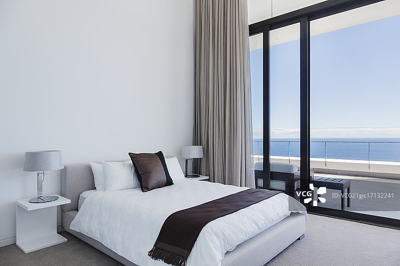 俯瞰大海的现代卧室中的床和灯图片素材