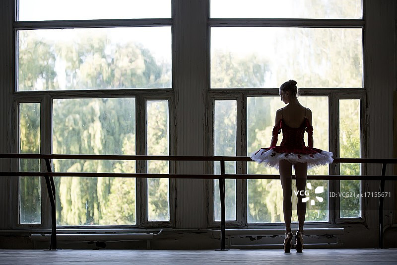 优雅的年轻芭蕾舞演员站在一扇大窗户旁跳舞图片素材