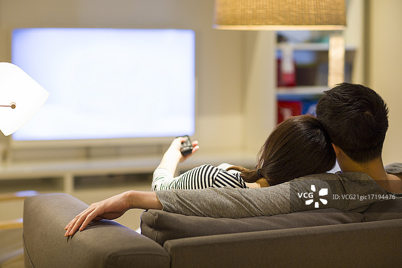 年轻情侣在客厅沙发上看电视图片素材