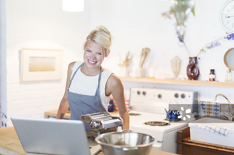 在厨房用笔记本电脑做饭的女人图片素材