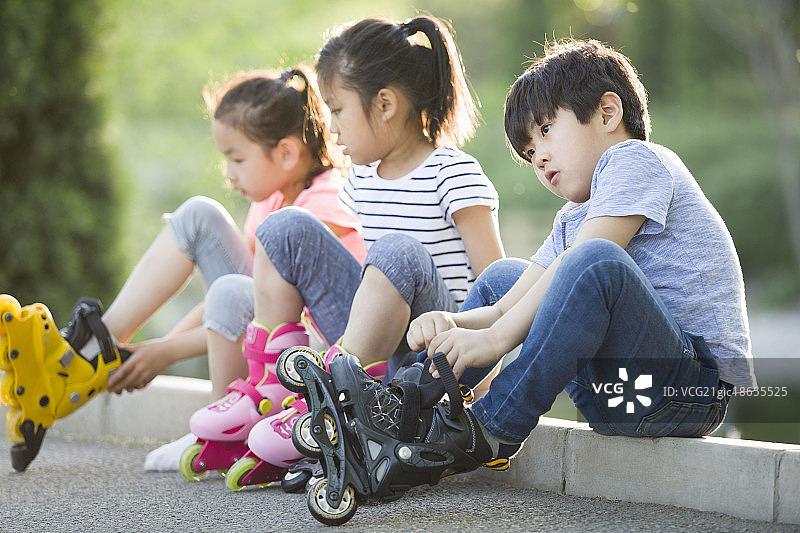 儿童坐在路边穿直排轮鞋图片素材