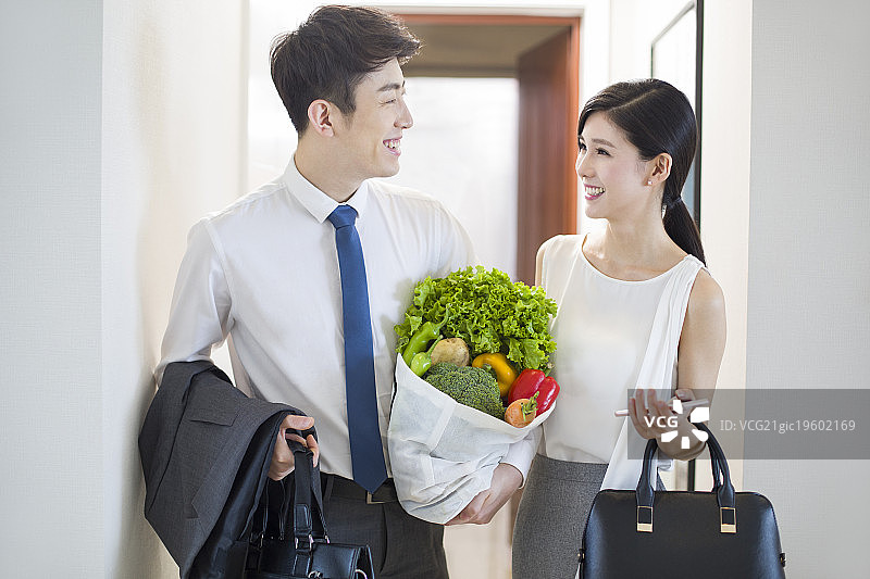 年轻夫妇下班买了蔬菜回家图片素材
