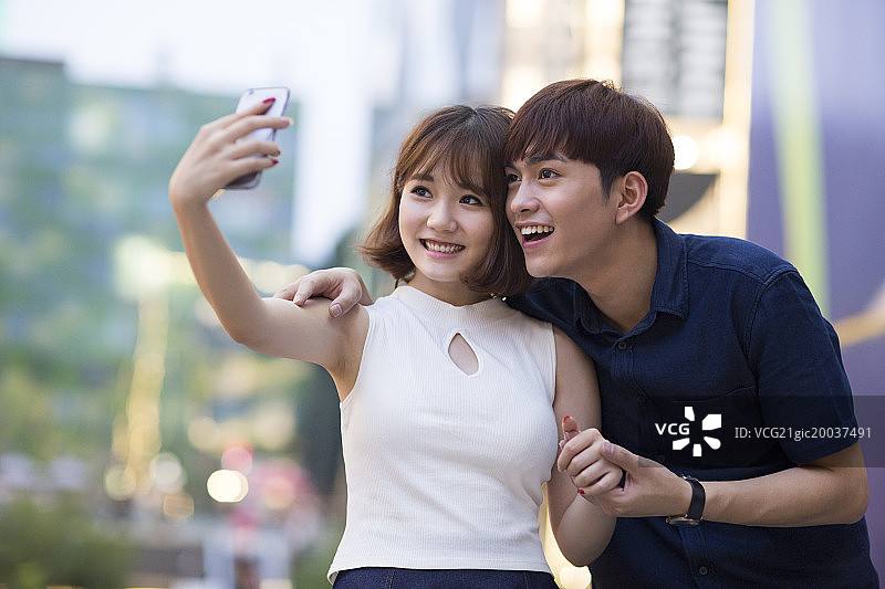 快乐的年轻情侣用手机自拍图片素材