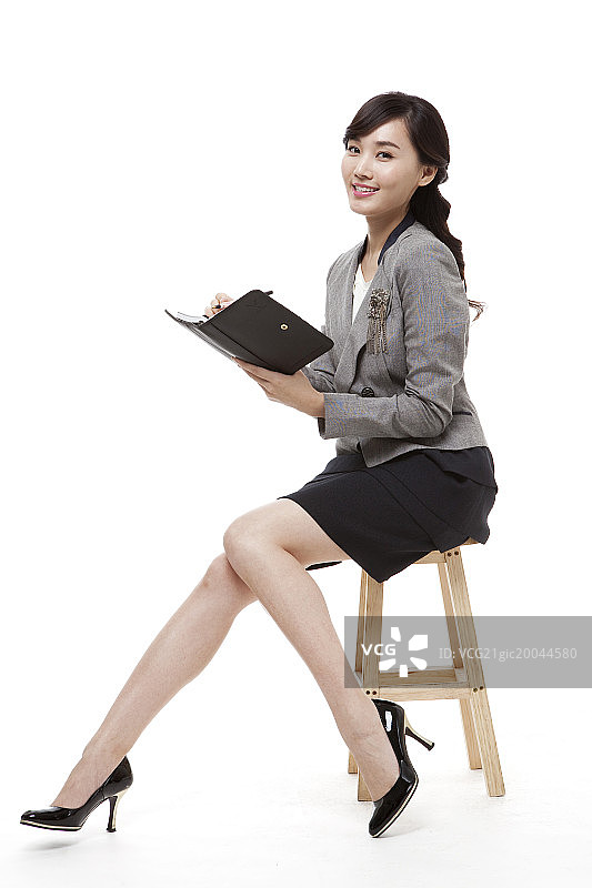 女商人拿着钢笔和日记本坐在椅子上图片素材