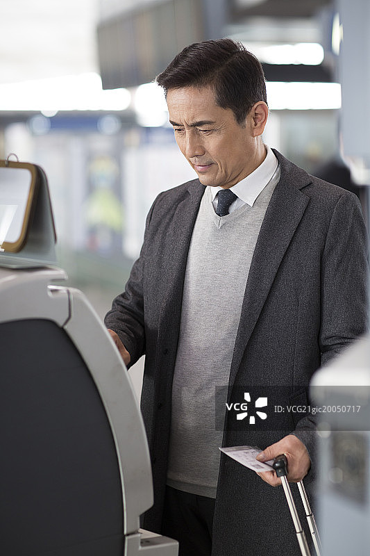 商务男士在机场使用自动售票机图片素材