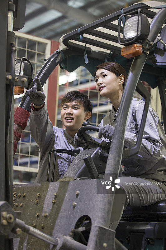 自信的年轻工人在工厂里驾驶叉车图片素材