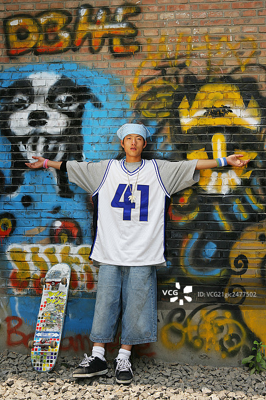 滑板男青年站在798艺术区内的涂鸦画前图片素材