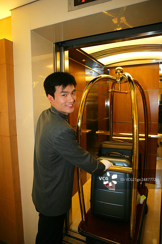 酒店服务生推行李车走进电梯图片素材