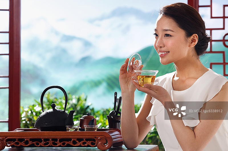 一个东方女孩在茶园的茶舍喝茶图片素材