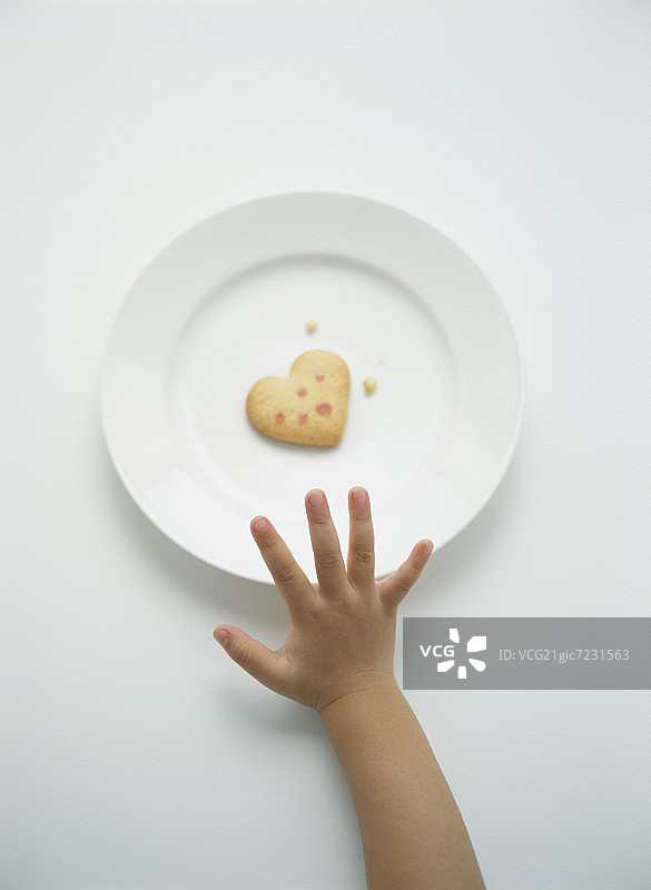 一个孩子的手伸向一个心形的饼干图片素材