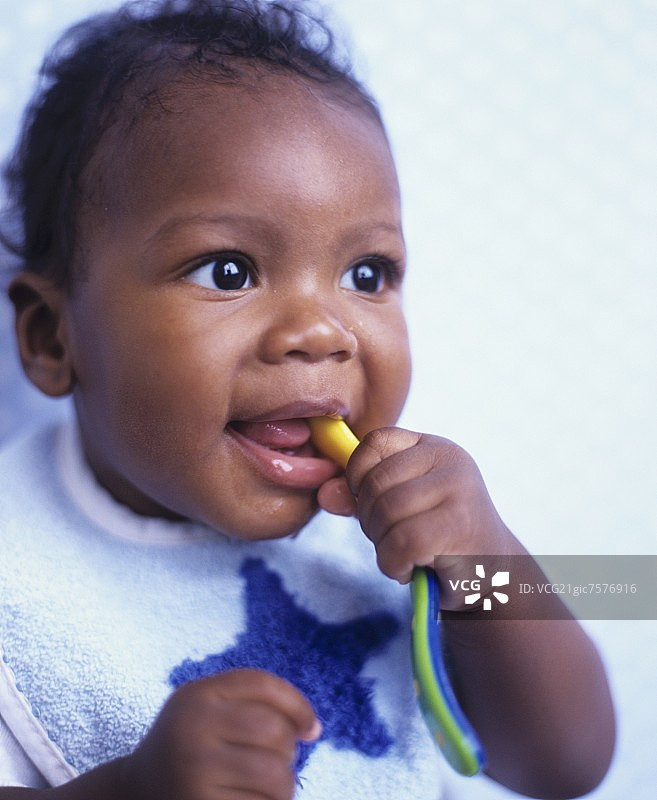 婴儿嚼着塑料勺图片素材