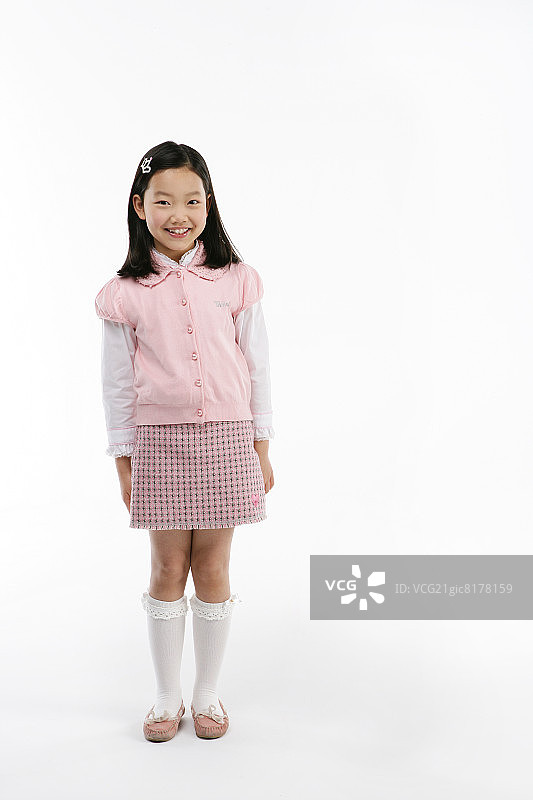 女孩(12-13岁)穿着开襟羊毛衫和格子裙，面带微笑，人像图片素材
