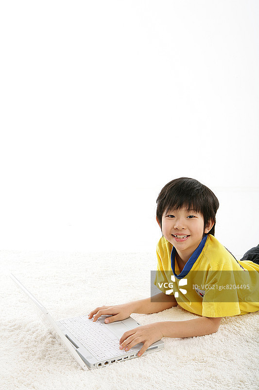 男孩(12-13岁)躺在地毯上，带着笔记本电脑，肖像，微笑图片素材