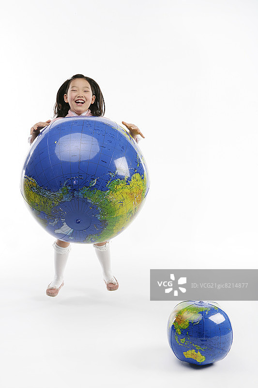 女孩(12-13岁)在玩地球仪，面带微笑图片素材