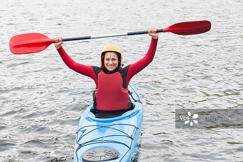 在冰冷的湖面上，一名女子在皮划艇上对着镜头微笑欢呼图片素材