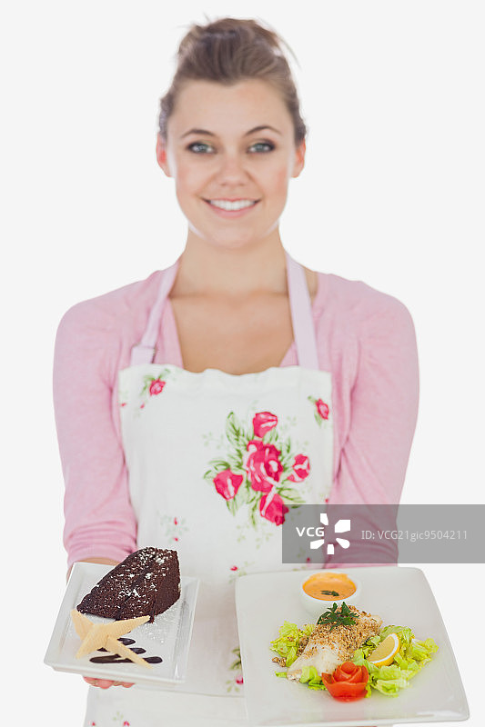 年轻妇女的肖像在围裙拿盘子的糕点和健康的膳食在白色的背景图片素材