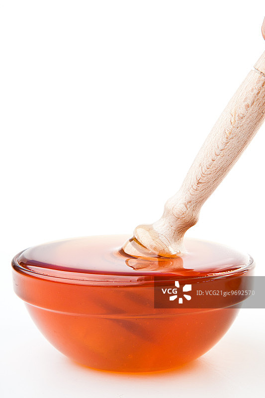 蜂蜜勺在蜂蜜碗在白色的背景图片素材