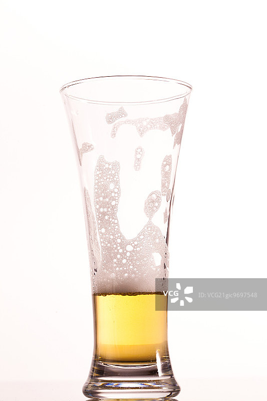 白背景下几乎空了的啤酒杯图片素材