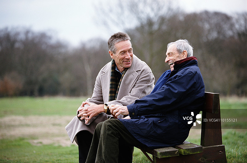 80多岁的父亲和50多岁的儿子在公园长椅上，英国图片素材