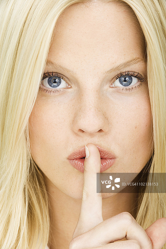 年轻女子手指放在嘴唇上，特写图片素材