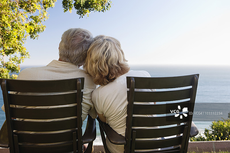 一对老年夫妇坐在露台上俯瞰大海图片素材