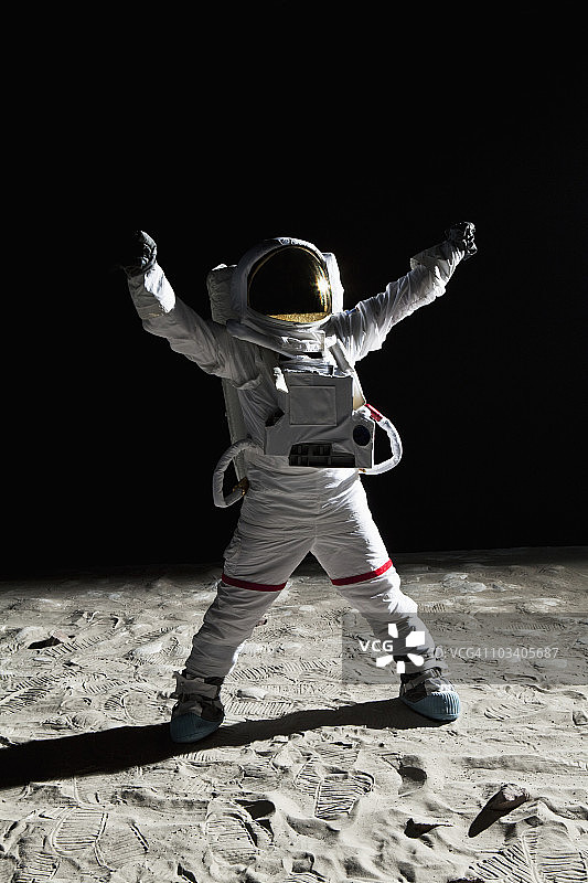 一名宇航员在月球上举起手臂庆祝胜利图片素材
