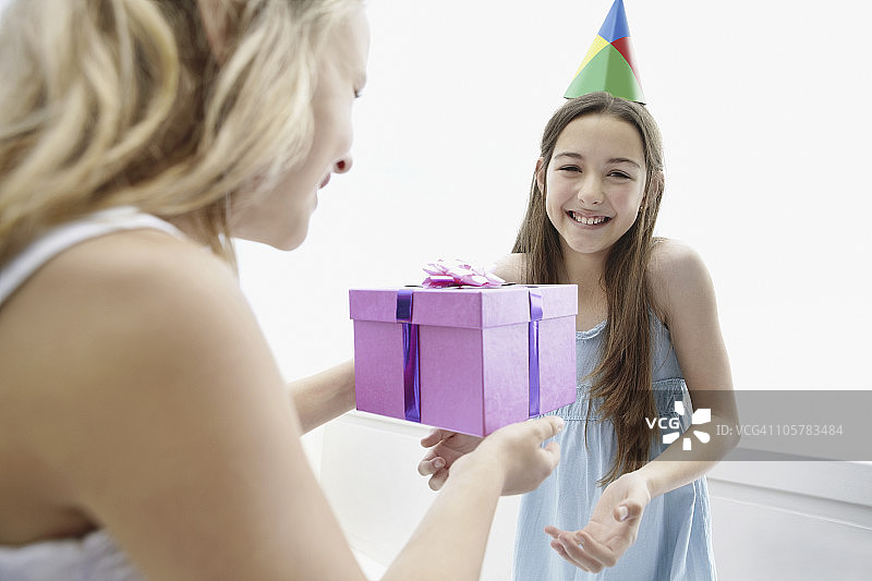 年轻的女孩给她的朋友一个生日礼物图片素材