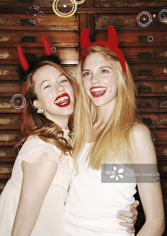 两个长着魔鬼角的年轻女人在笑图片素材
