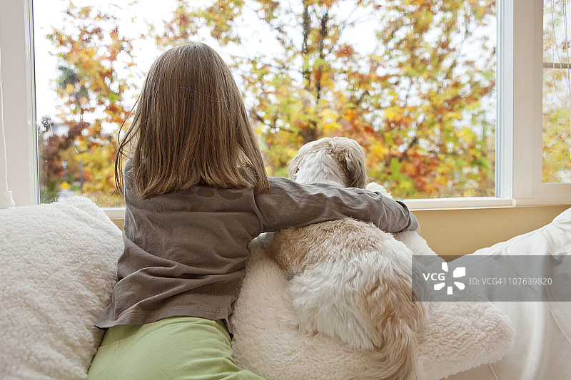 小女孩和她的狗往窗外看图片素材