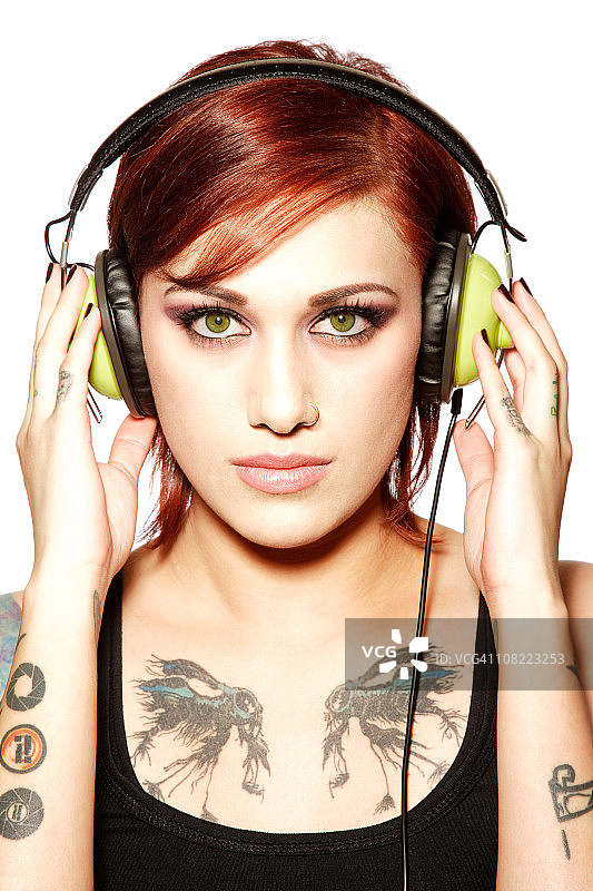 年轻的纹身女子听耳机图片素材