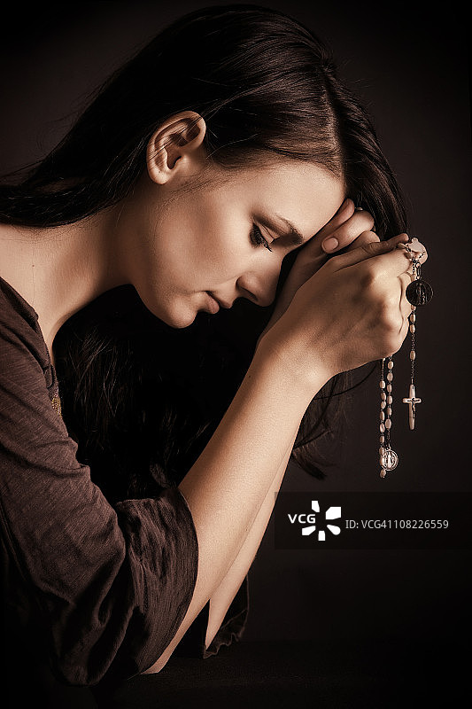 年轻女子用念珠祈祷图片素材