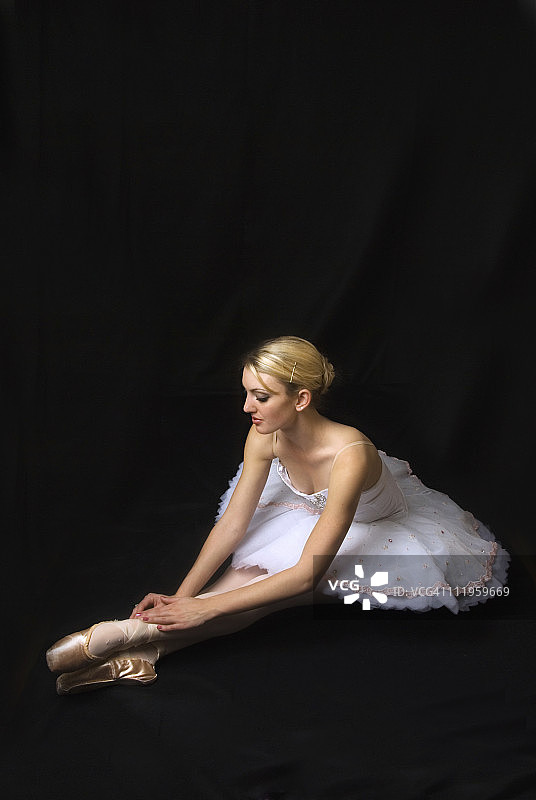 坐在黑色背景上的芭蕾舞女演员图片素材